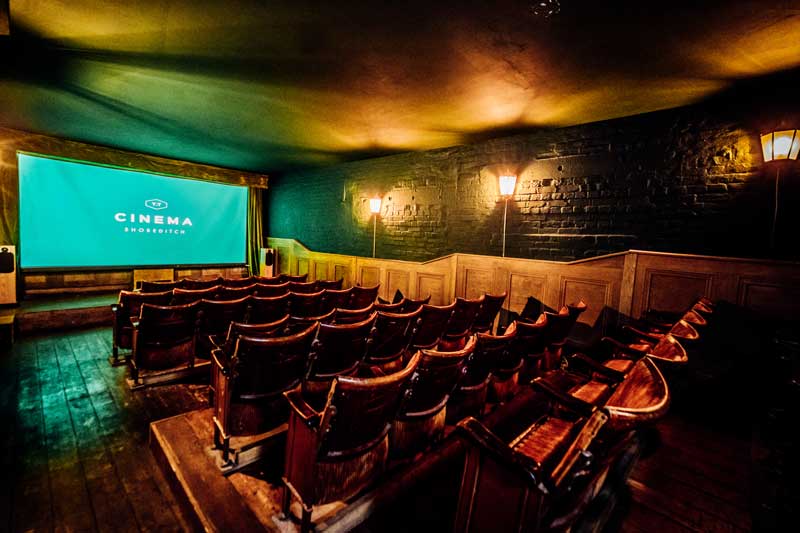 Indoor cinema with seats facing large screen.
