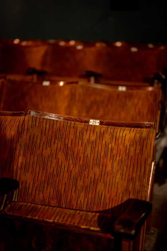 Close up of traditional cinema seats with seat numbers on them.